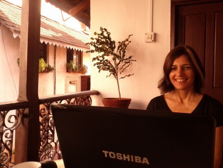 Ulrike Rodrigues (Girl Gone Goa) sits at a Panjim Inn balcony with a laptop computer in Goa, India.